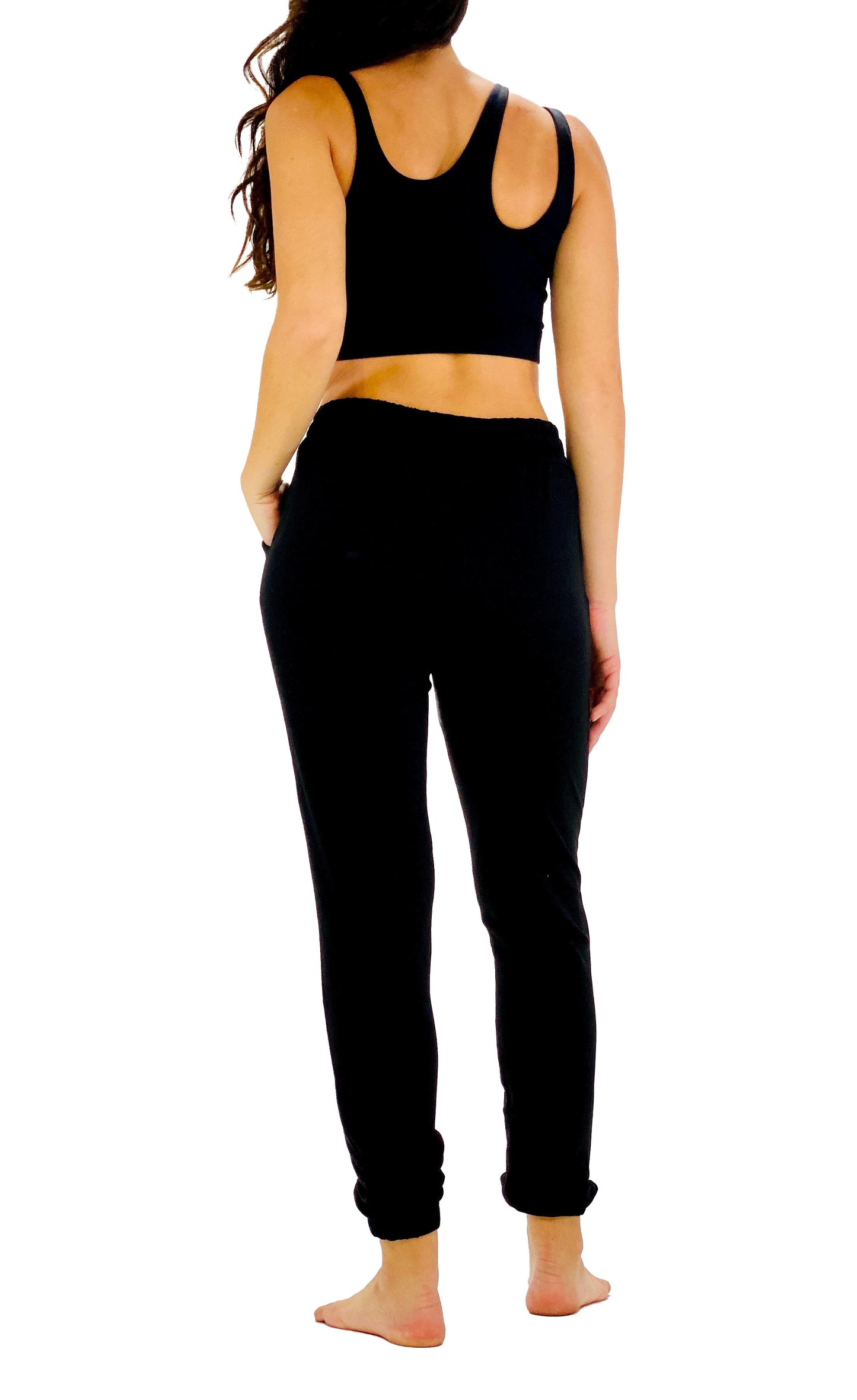 A woman shown from the back wearing a black sports bra and black jogger pants against a plain white background.