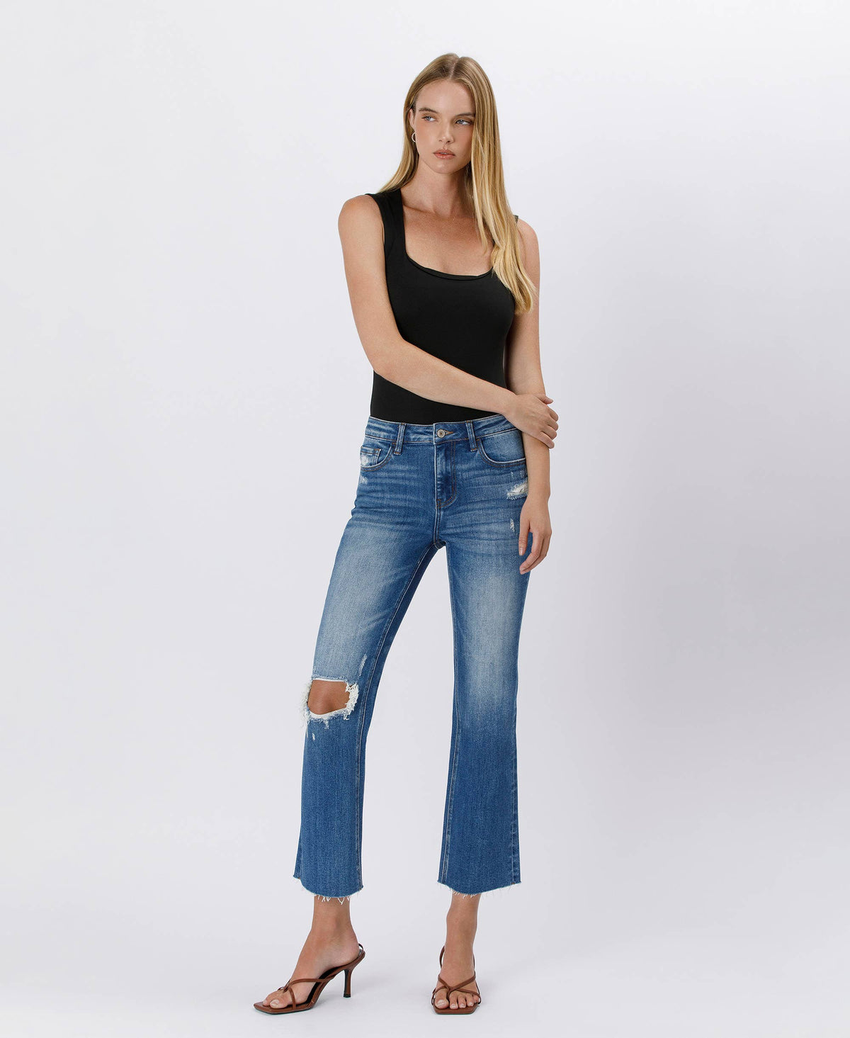 Woman wearing blue jeans and a black top on a white background