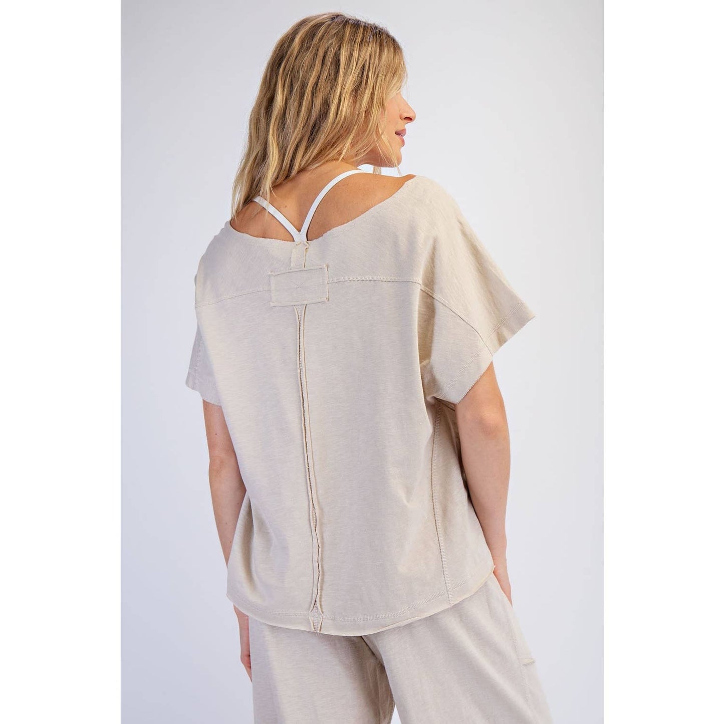 Woman wearing a beige top and pants on a white background