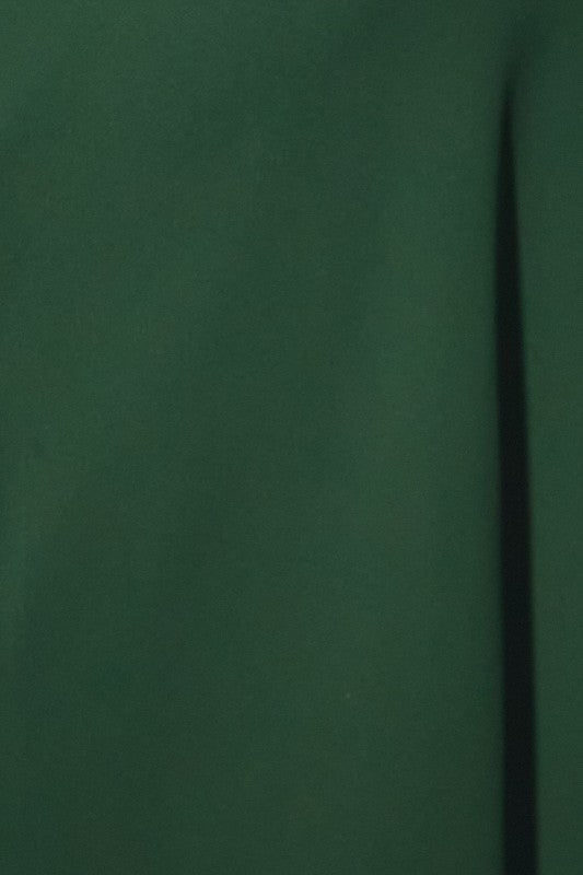 A close-up of a dark forest green fabric surface with a vertical seam or fold running down the right side.