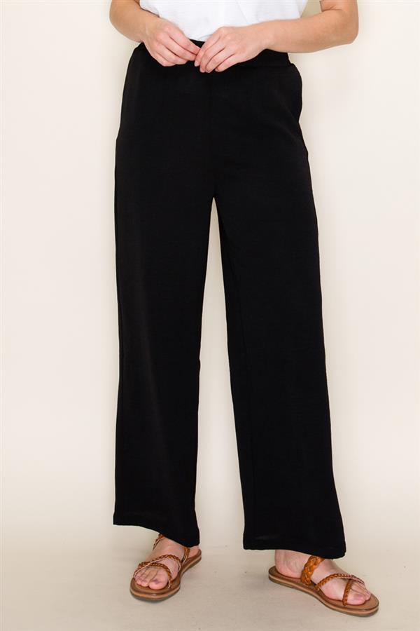 Person wearing black pants and sandals on a plain background