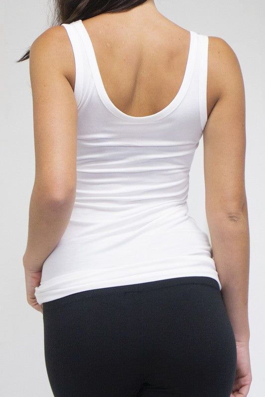 Person wearing a white tank top and black pants on a plain background