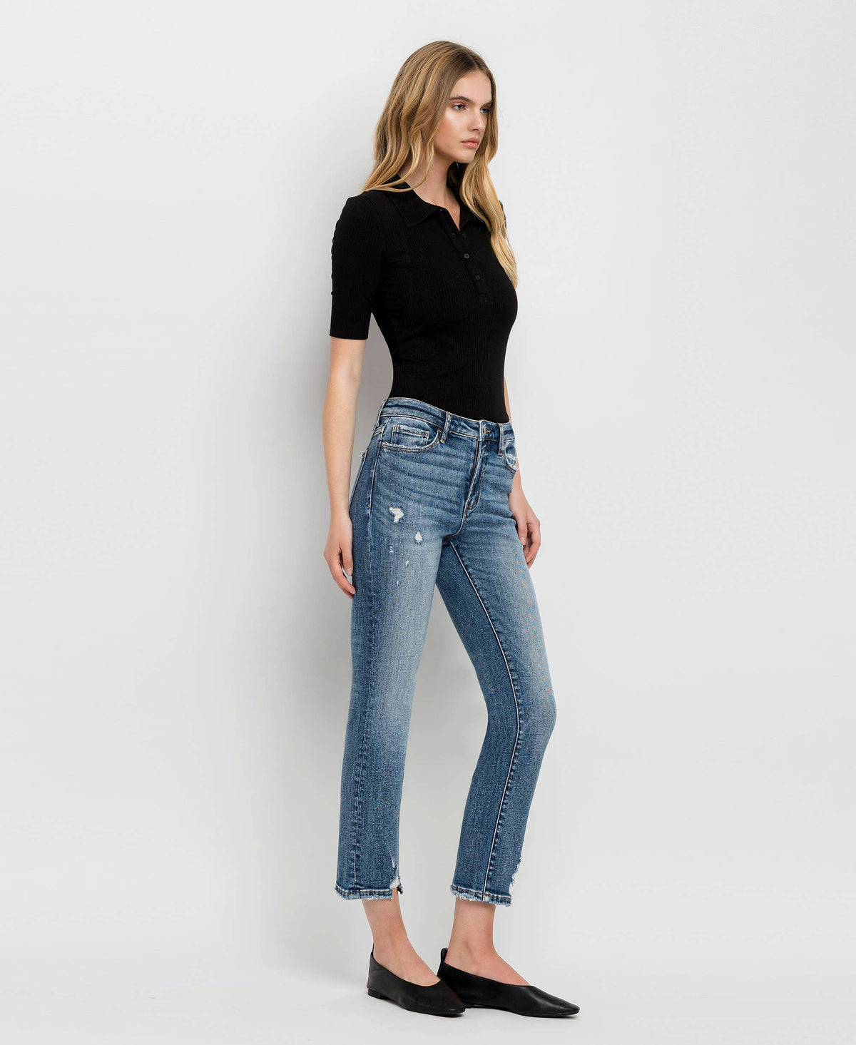 Woman wearing blue jeans and a black top on a white background