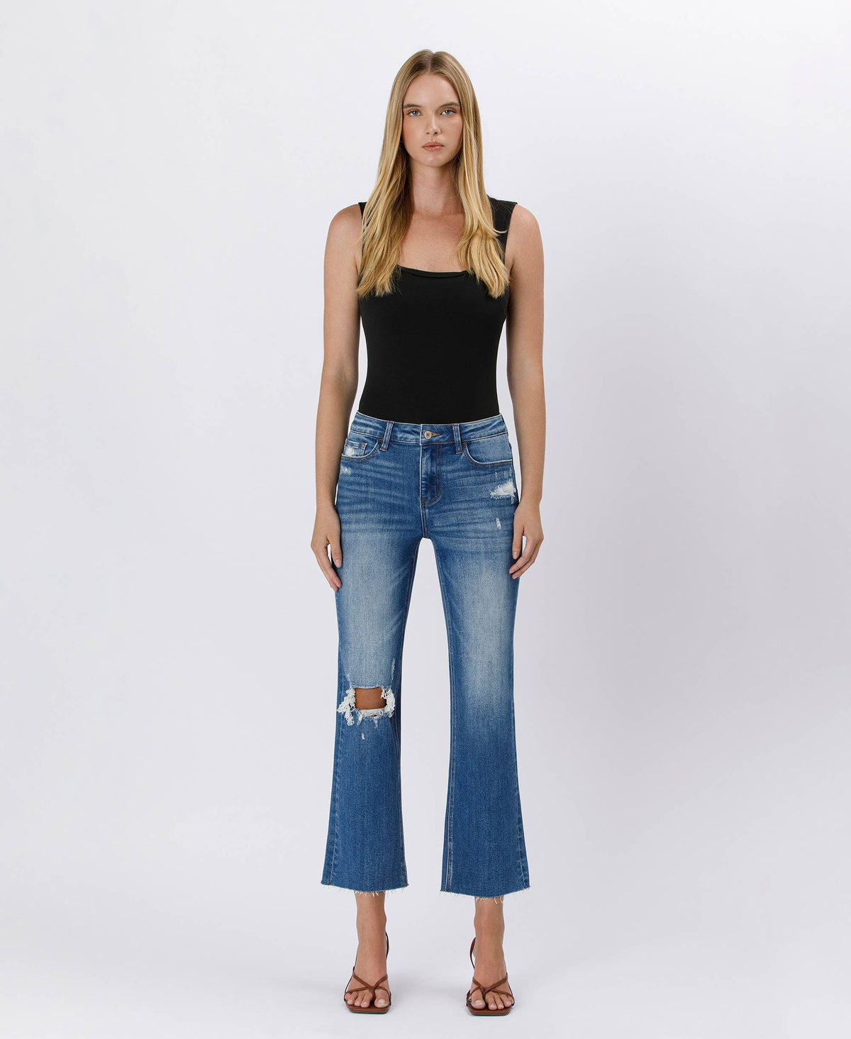 Woman wearing blue jeans and a black top on a white background