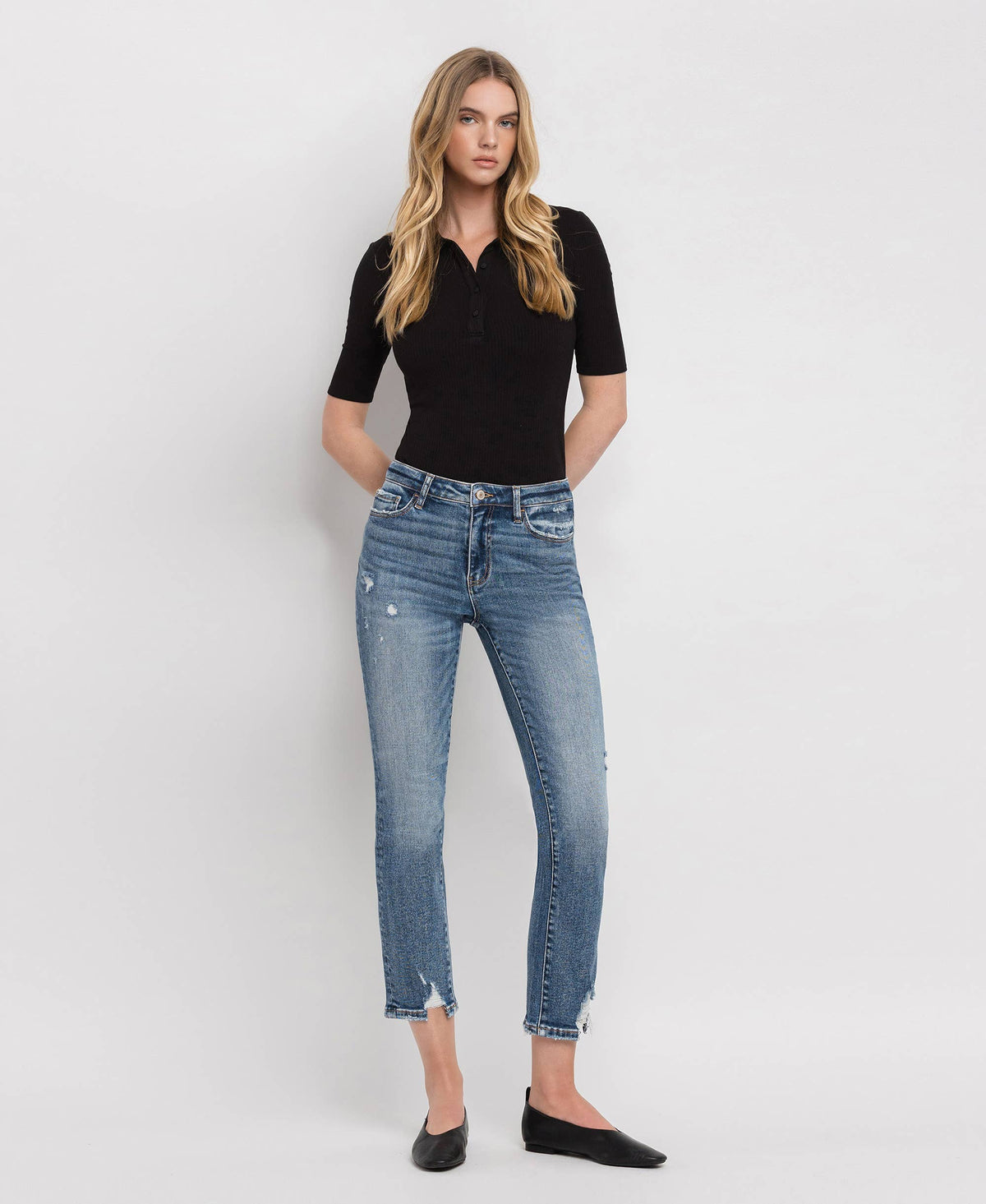 Woman wearing a black top and blue jeans on a white background
