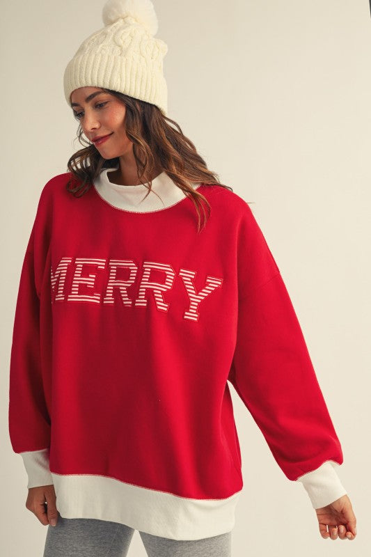 Apricot Lane Duluth oversized red Christmas top with MERRY text, mock neck, and white ribbed trim worn with a beanie