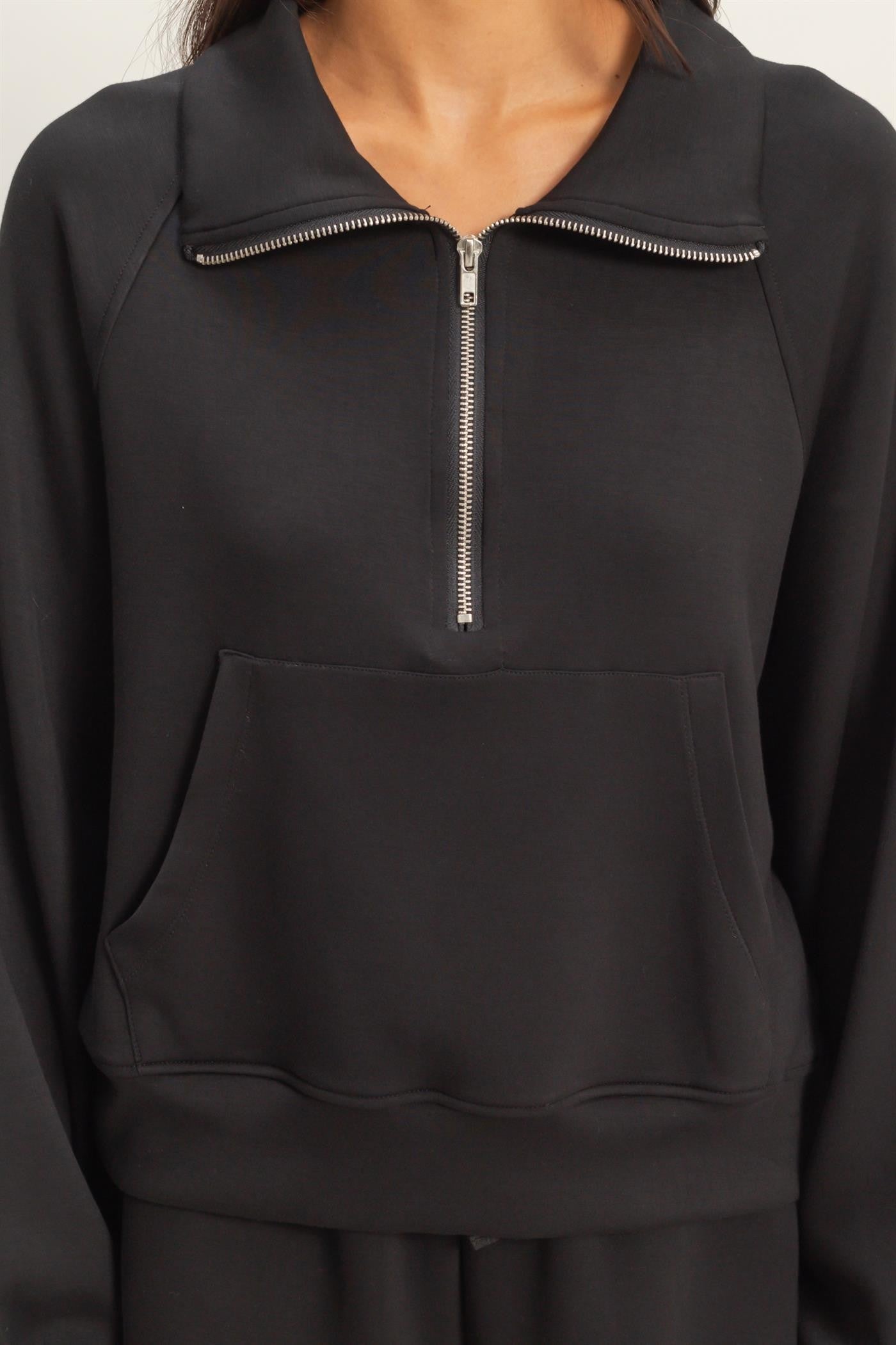 Black pullover with a zipper detail on a neutral background