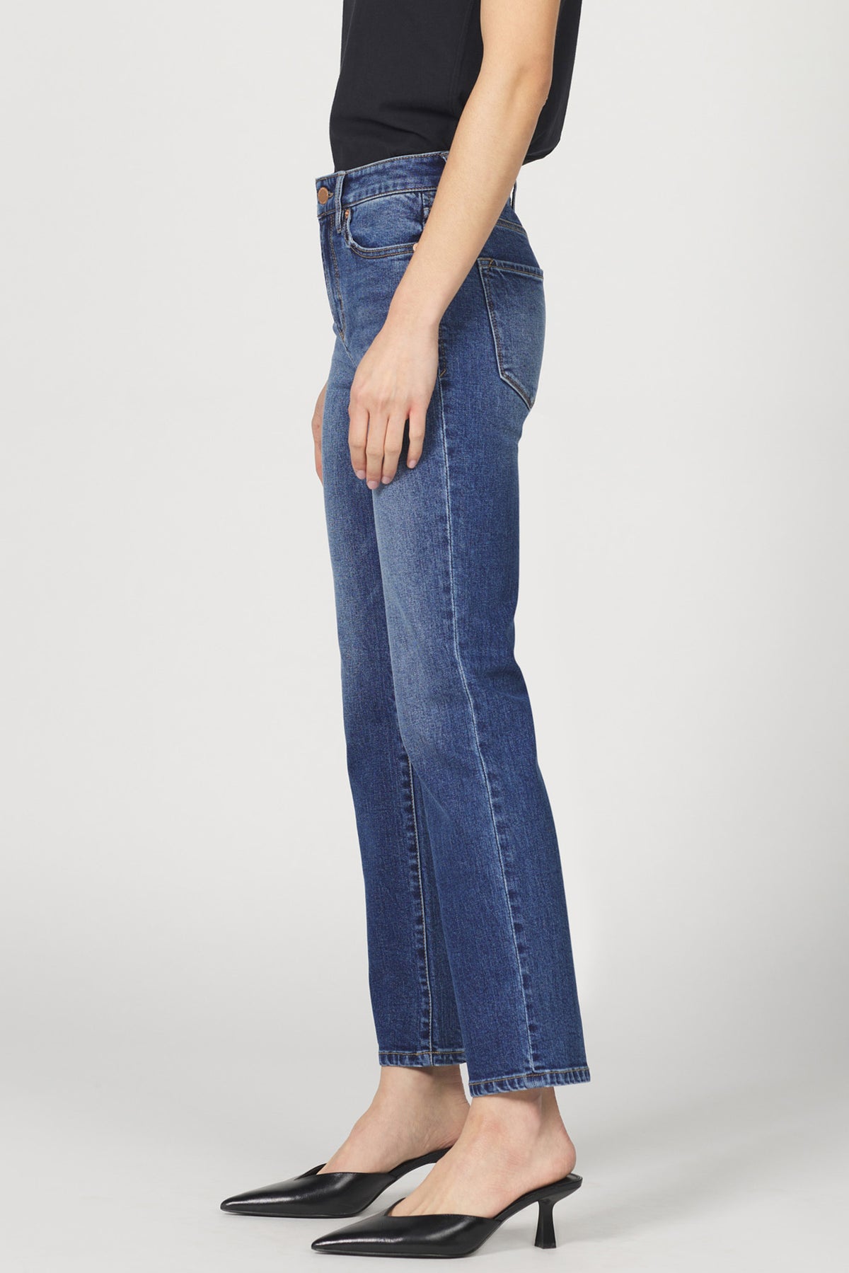 Person wearing blue jeans on a plain background