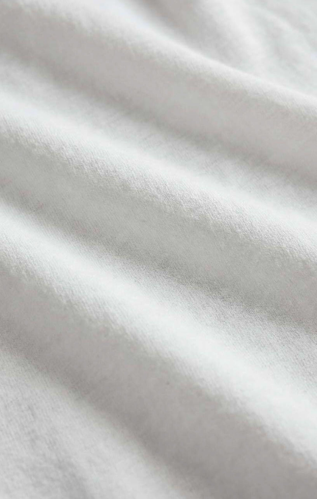 A close-up of soft white fabric with gentle folds and a smooth texture.