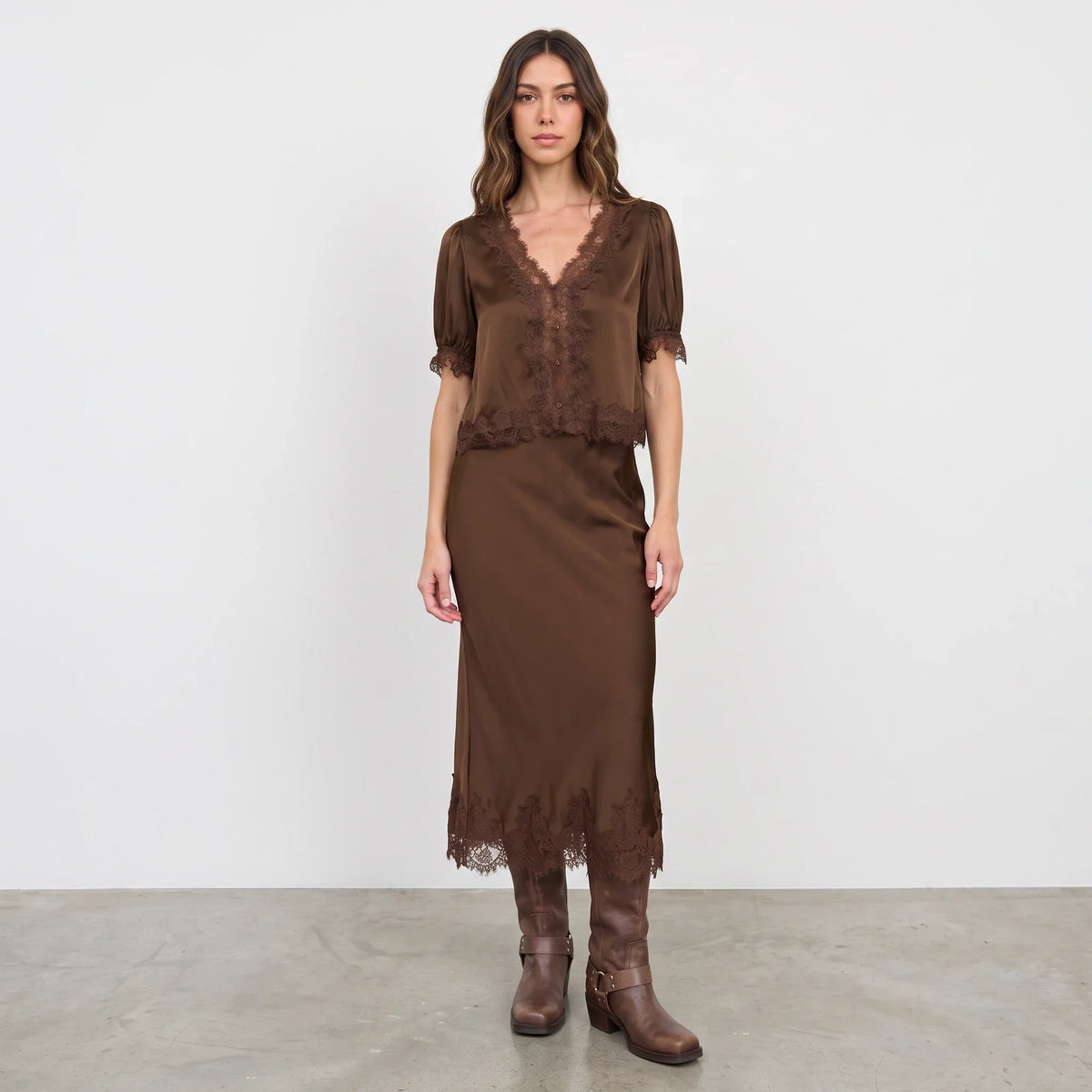 Model wearing Apricot Lane Duluth brown satin blouse with lace trim and matching midi skirt with brown leather boots