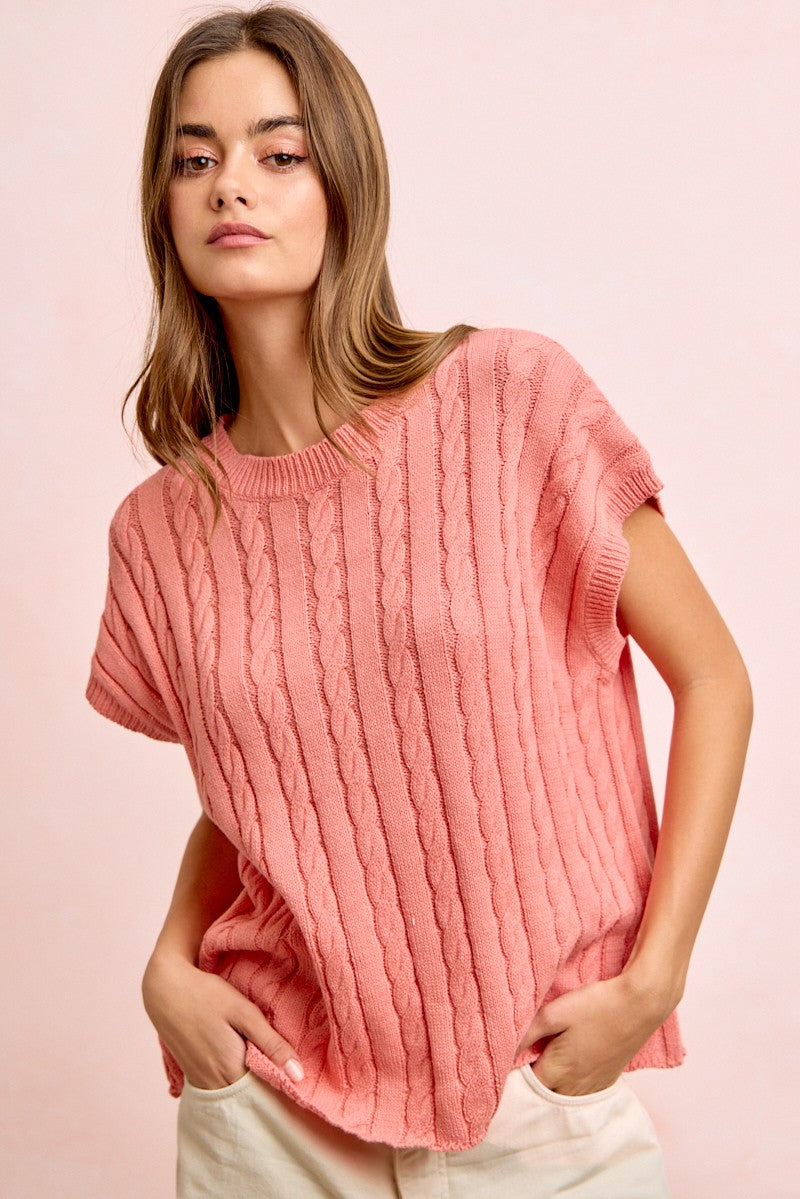 Woman wearing a pink ribbed sweater against a pink background