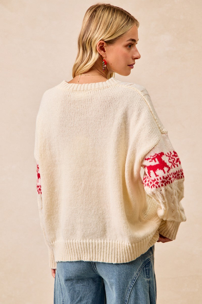 Woman wearing a cream sweater with red reindeer patterns on sleeves against a beige background