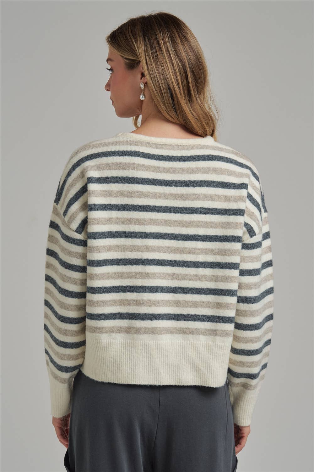 Woman wearing a striped sweater with a neutral background