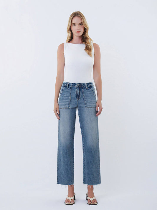 Woman wearing a white sleeveless top and blue jeans on a white background