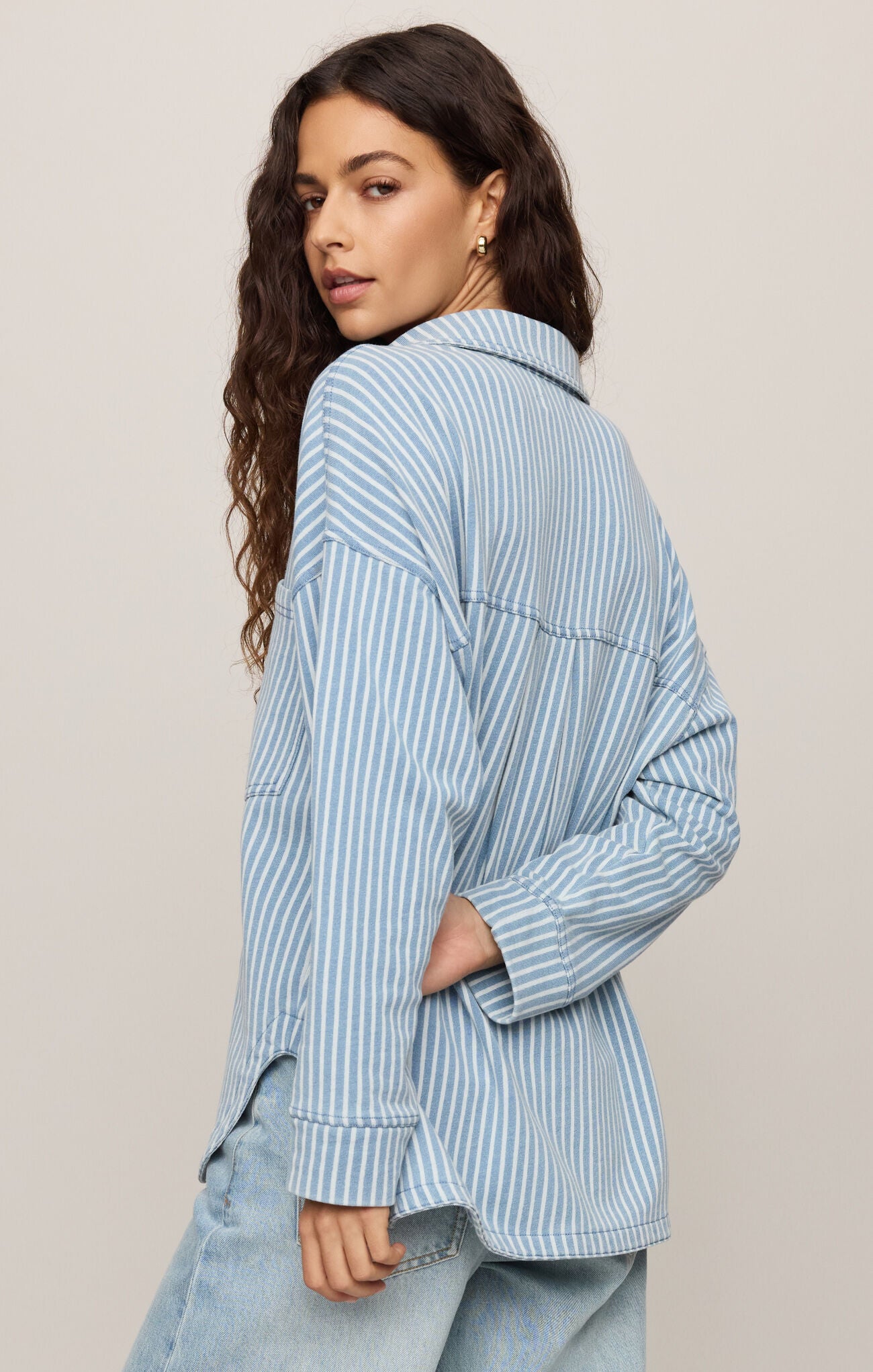 Woman wearing a blue striped shirt against a beige background