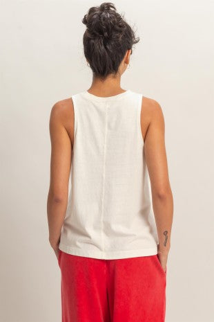 Person wearing a white sleeveless top and red pants on a plain background