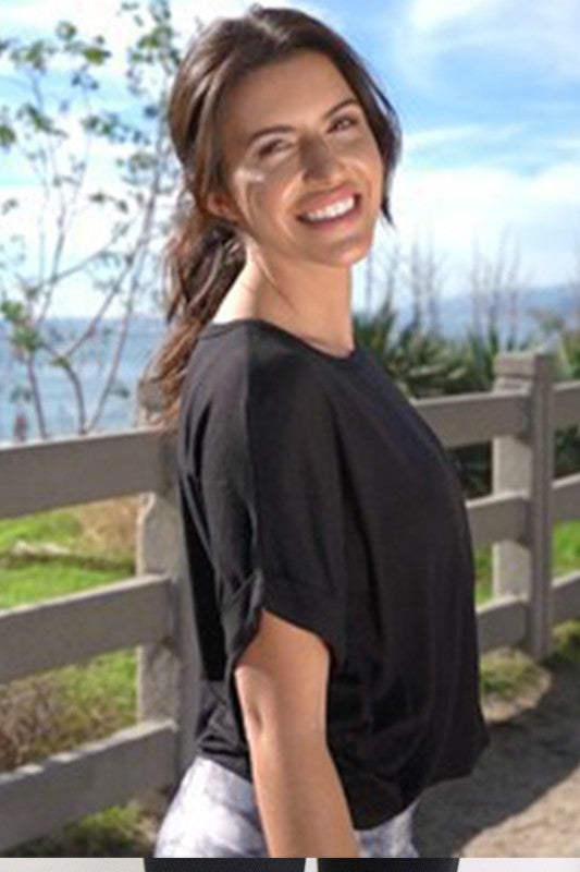 Woman wearing a black shirt standing outdoors with a scenic background