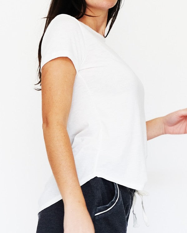 Person wearing a white sleeveless top with a blurred background