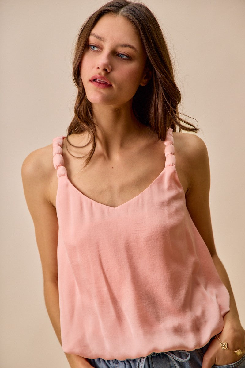 Woman wearing a pink tank top against a beige background