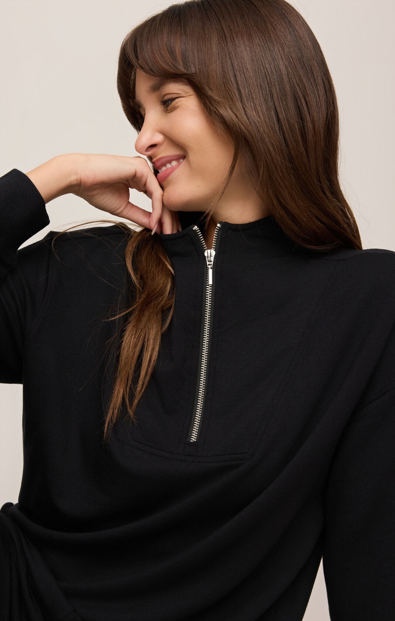 Woman wearing a black zip-up sweatshirt against a plain background