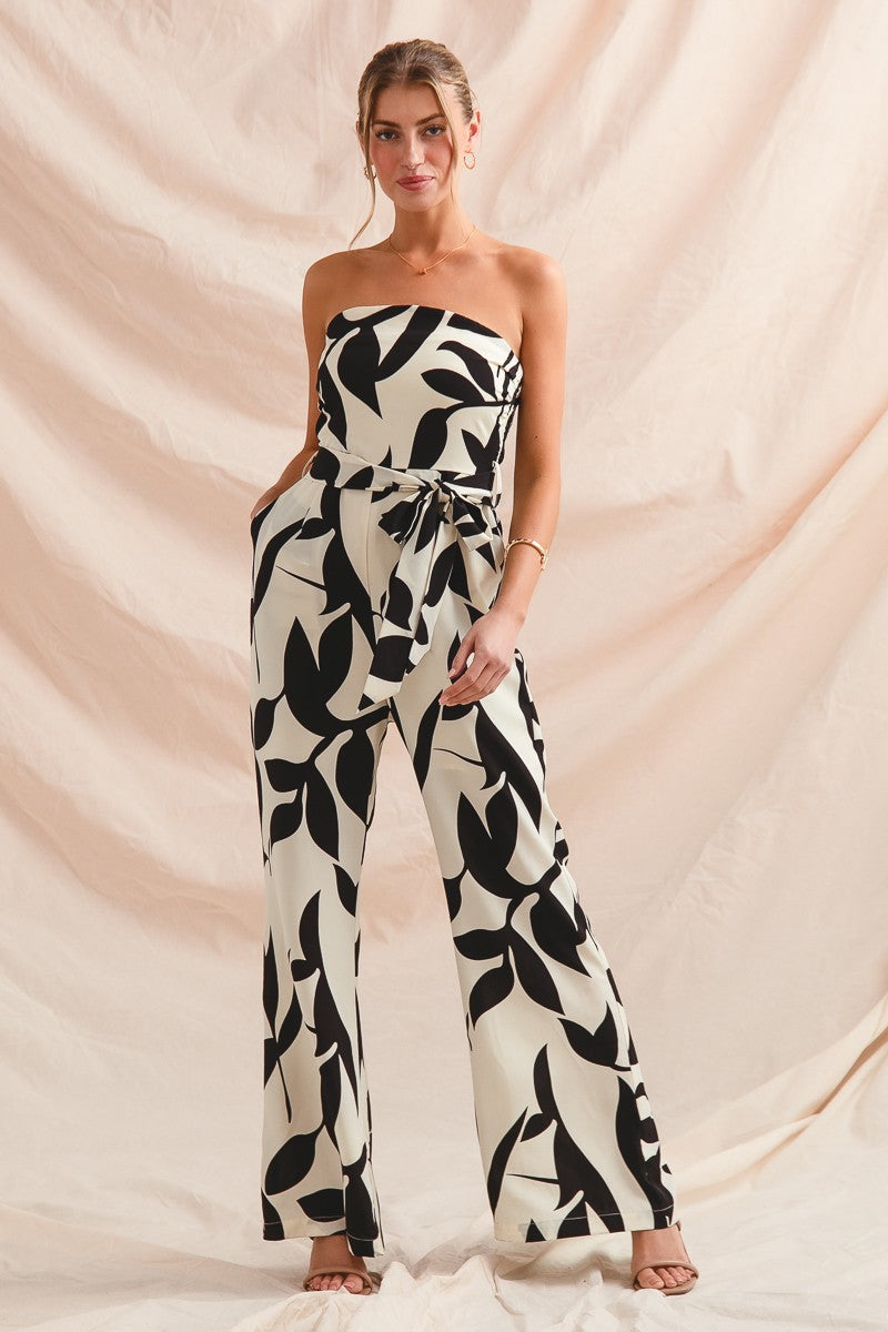 Woman wearing a strapless jumpsuit with black leaf pattern on a beige background