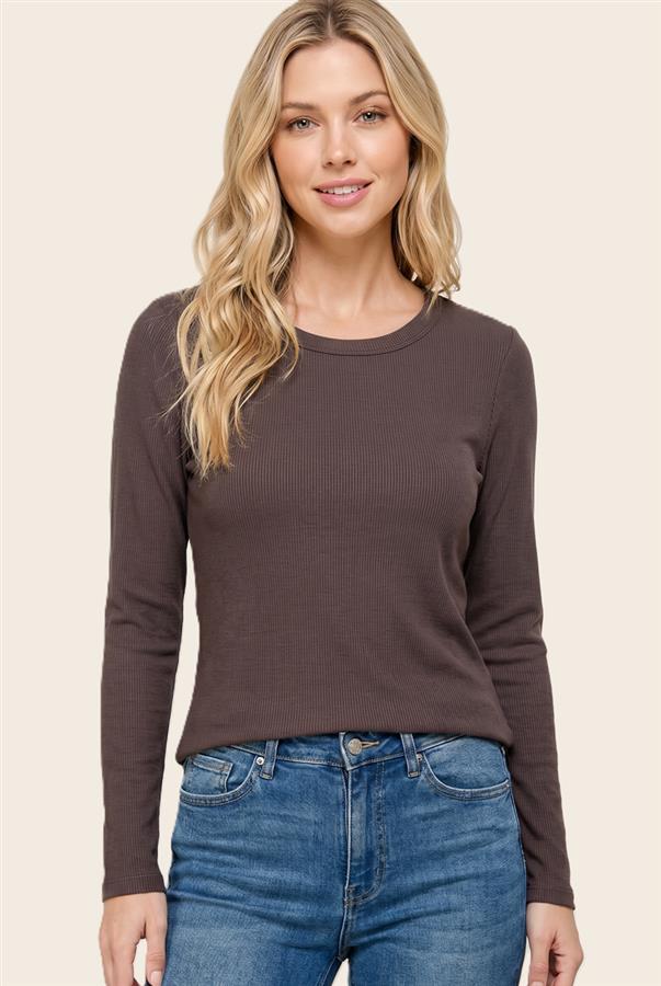 A woman wearing a dark brown long-sleeve ribbed knit top and blue jeans, standing against a solid light beige background.