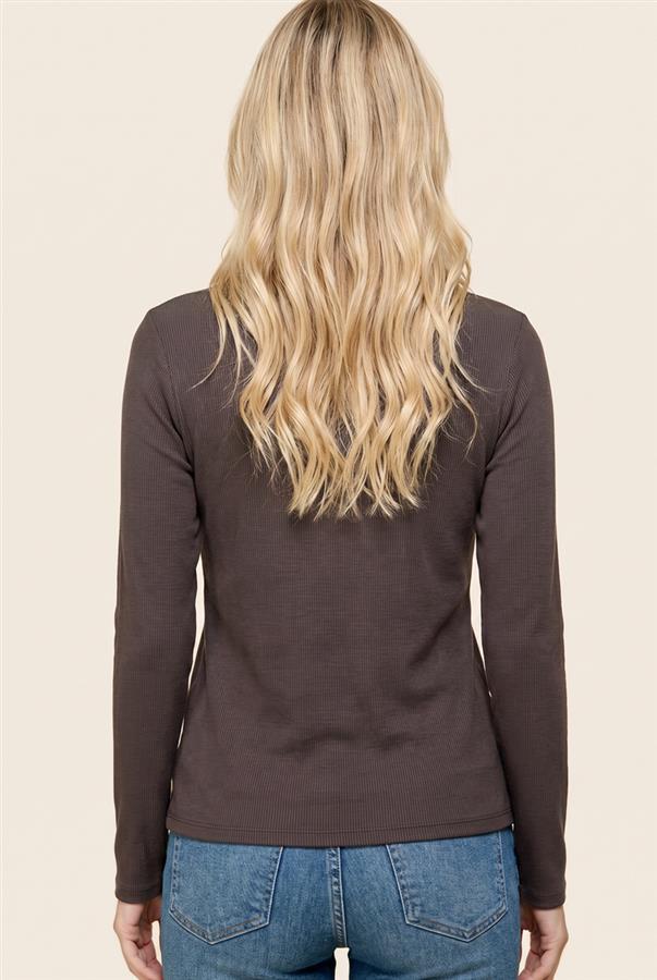 A woman viewed from the back wearing a dark brown long-sleeve knit top and blue jeans, set against a solid light beige background.