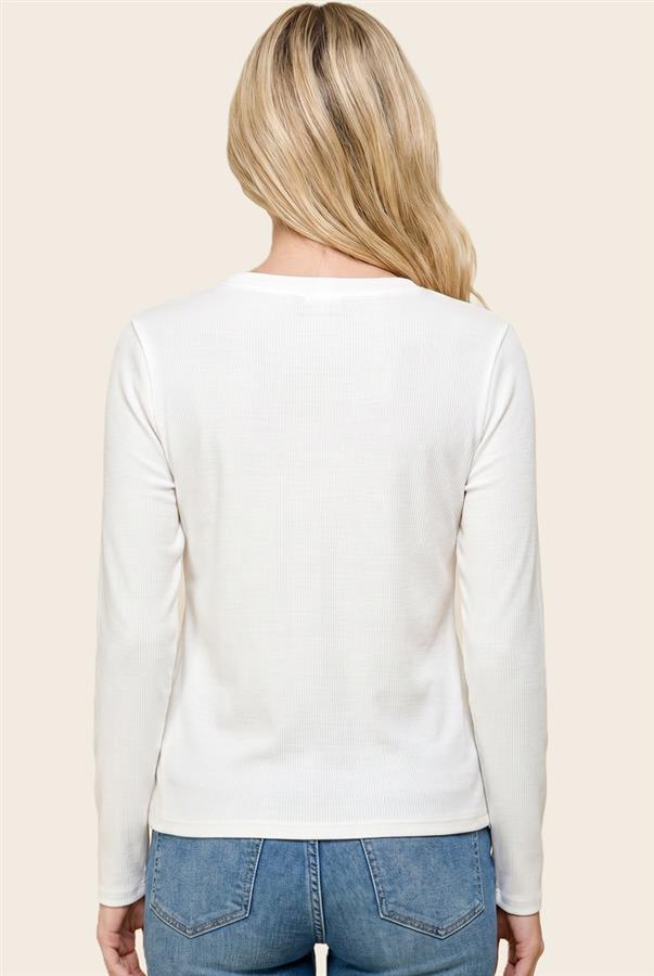 A woman viewed from the back wearing a fitted white long-sleeve top and blue jeans against a plain light beige studio background.