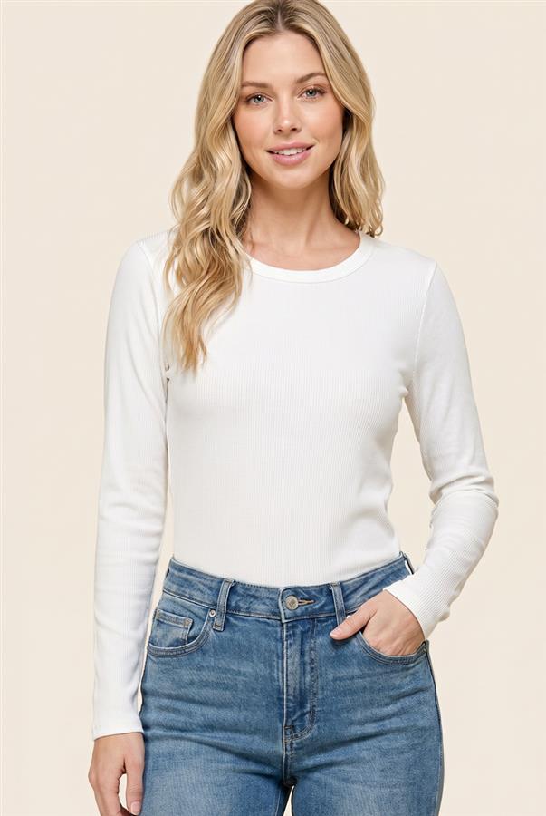 A woman with blonde hair wearing a white long-sleeve crewneck top and blue jeans, standing against a solid beige background.