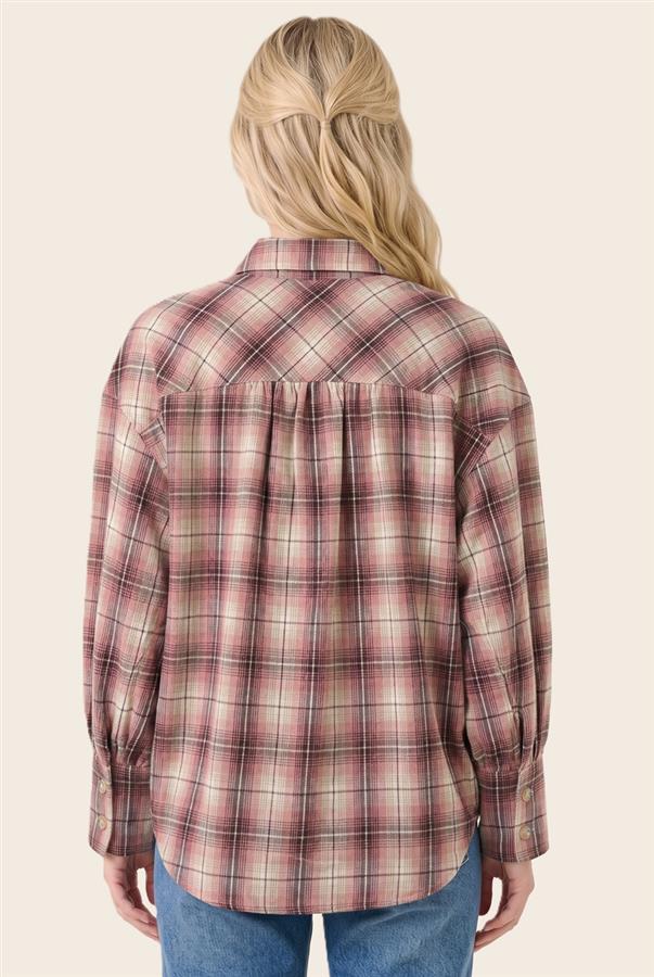 A woman viewed from the back wearing a long-sleeve plaid button-up shirt in muted pink, red, and beige tones, paired with blue jeans against a plain light beige studio background.