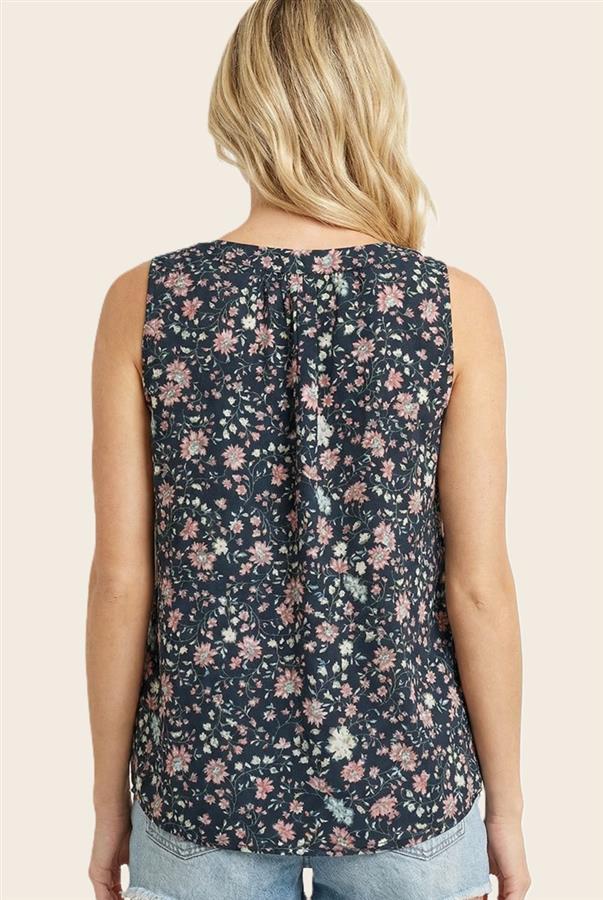 Woman wearing a sleeveless floral top against a beige background