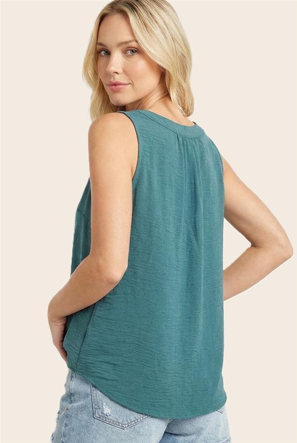 Woman wearing a teal sleeveless top against a beige background
