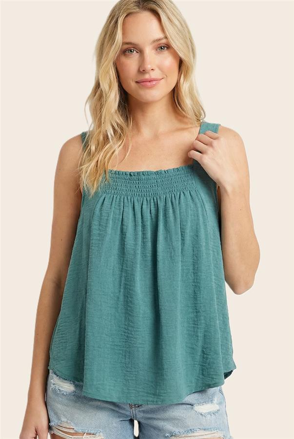 Woman wearing a teal sleeveless top with a beige background