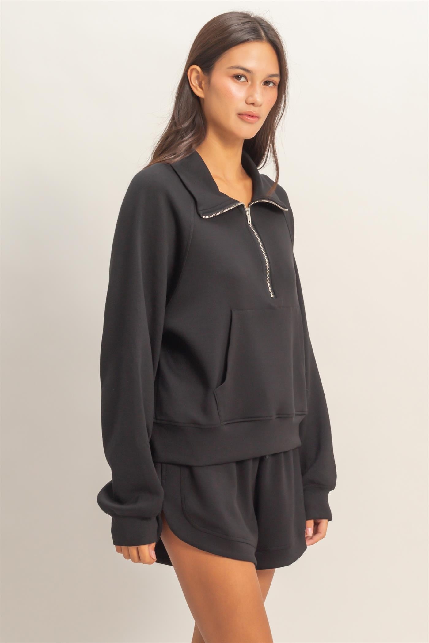 Woman wearing a black tracksuit against a plain background