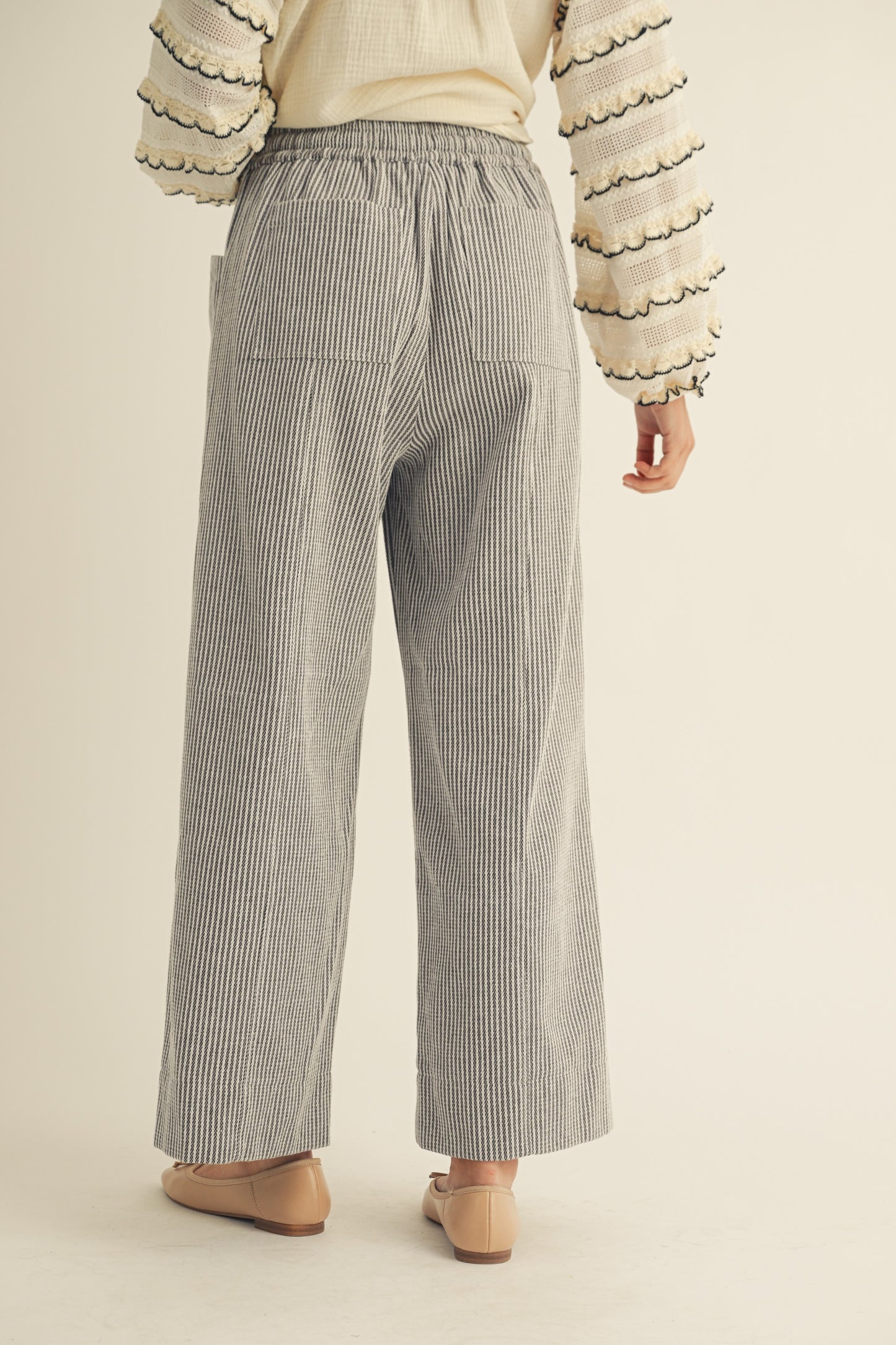 Person wearing gray striped pants on a beige background