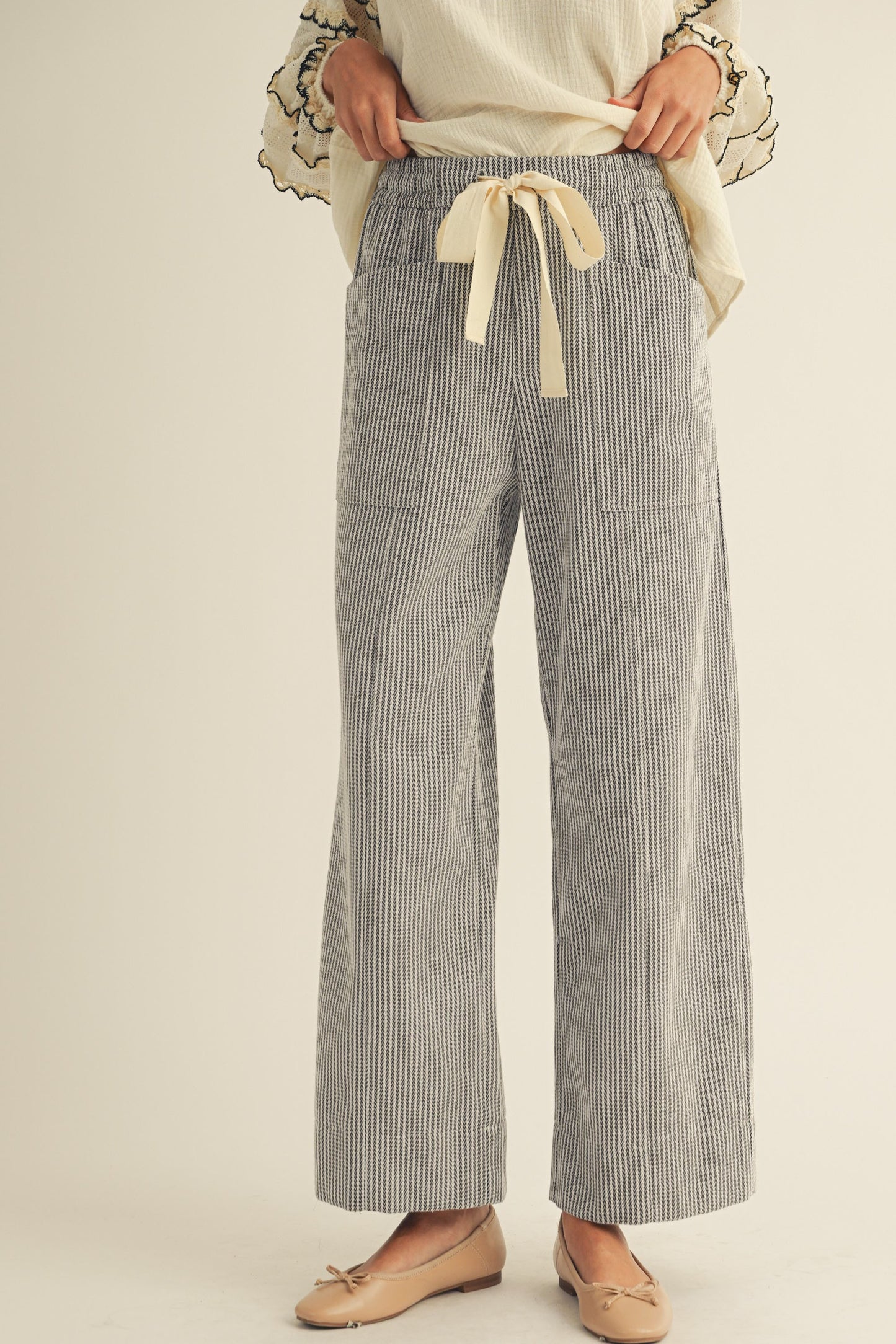 Striped pants with a tie waist on a plain background
