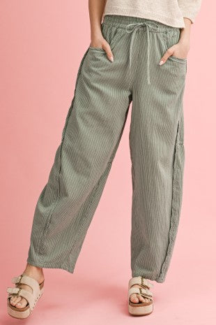 Person wearing green striped pants on a pink background