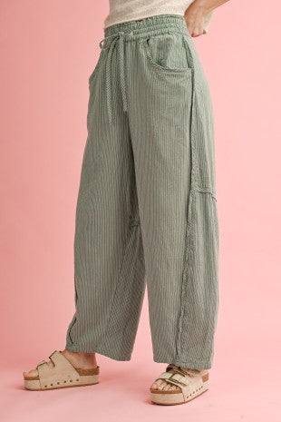 Green striped pants worn by a person on a pink background