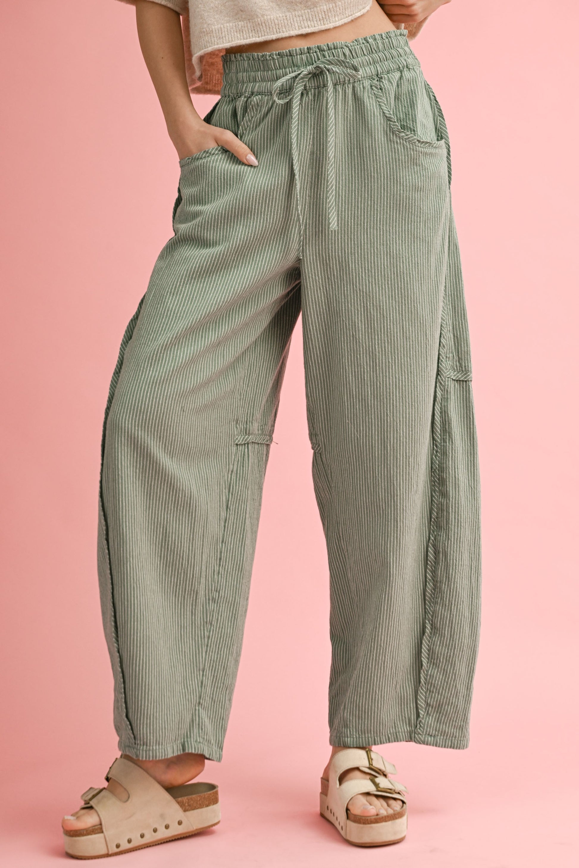Person wearing green striped pants on a pink background