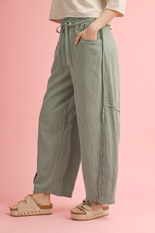 Person wearing green striped pants on a pink background