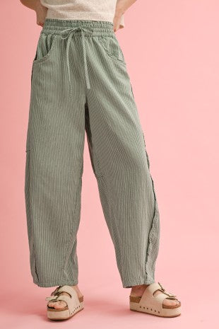 Person wearing green striped pants on a pink background