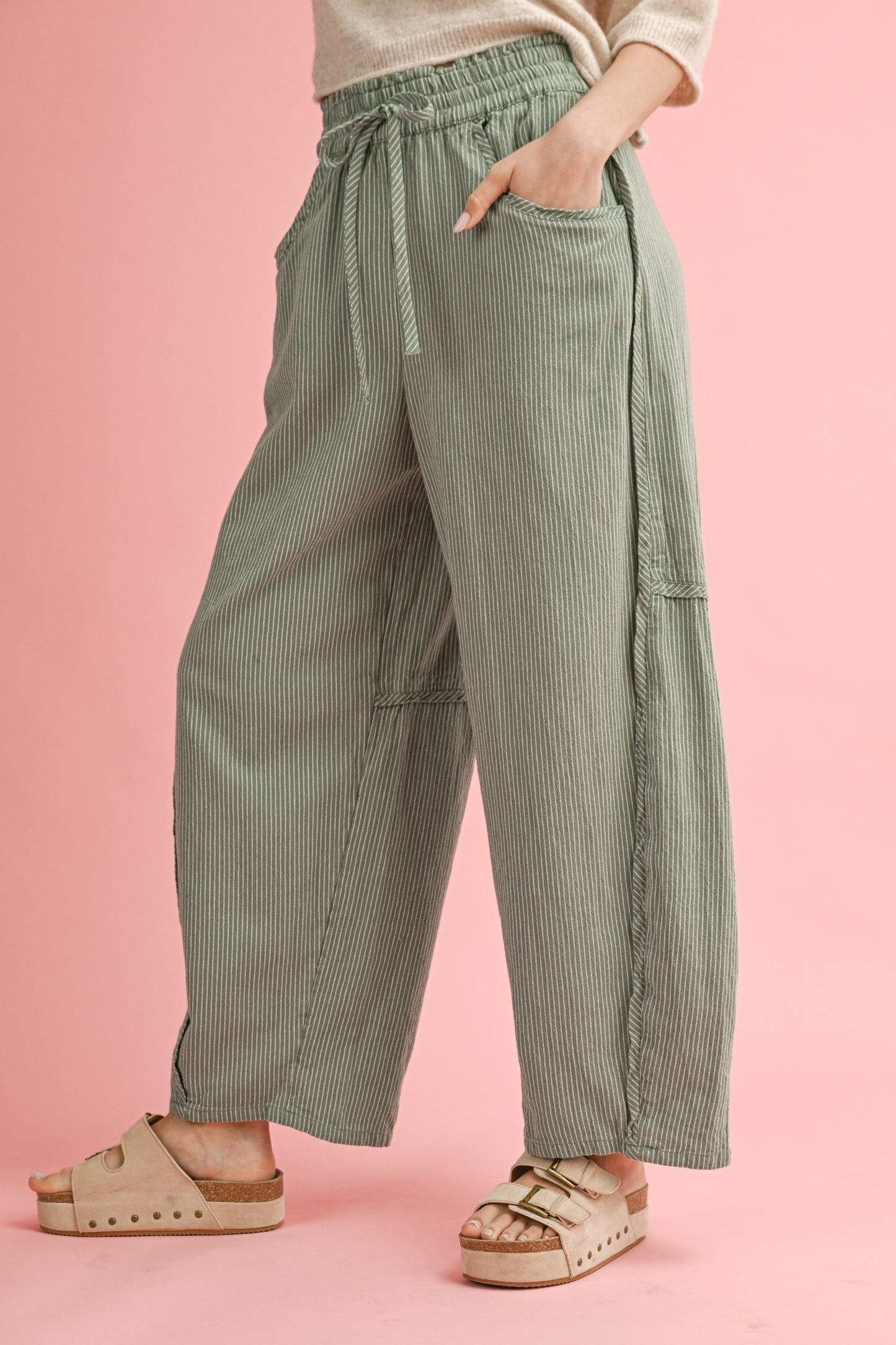 Person wearing green striped pants on a pink background