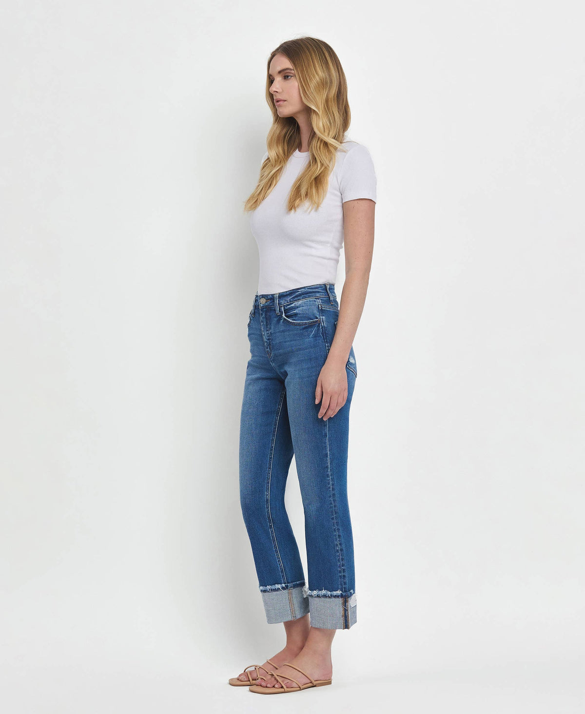 Woman wearing blue jeans and a white top against a white background