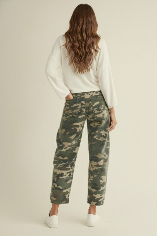 Woman wearing camouflage pants and a white top on a beige background