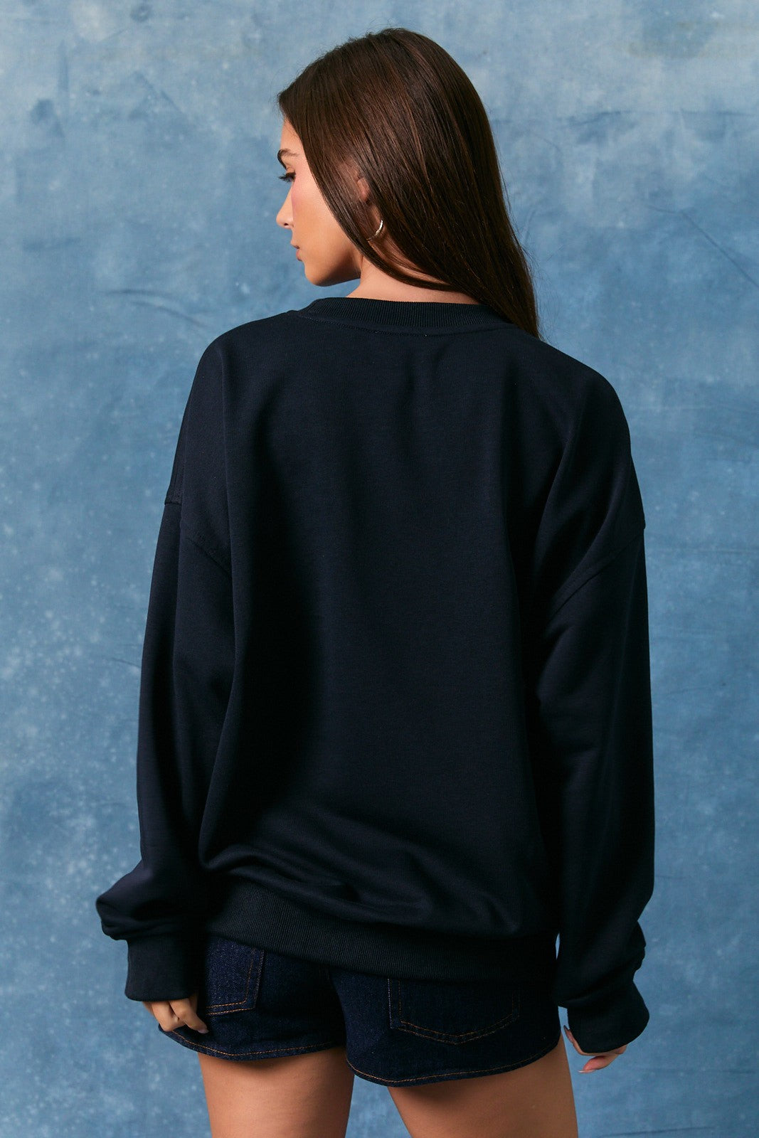 Person wearing a black sweatshirt against a blue textured background