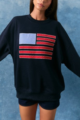 Person wearing a black sweatshirt with an American flag design on a blue background
