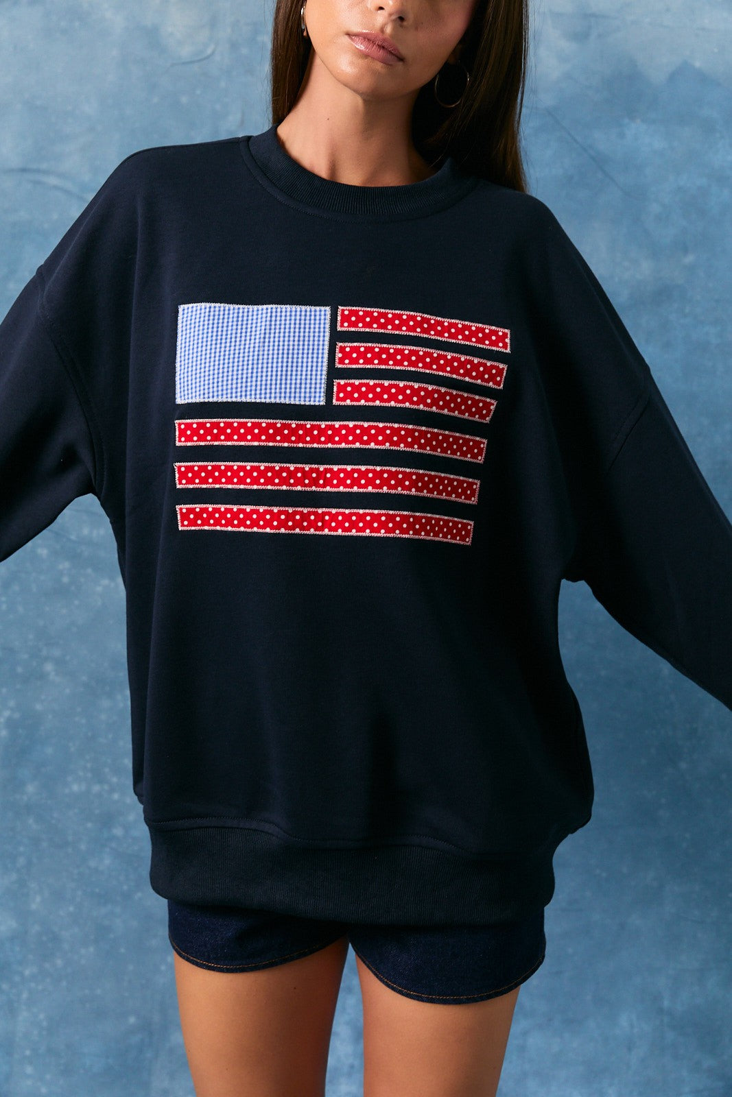 Person wearing a black sweatshirt with an American flag design on a blue background