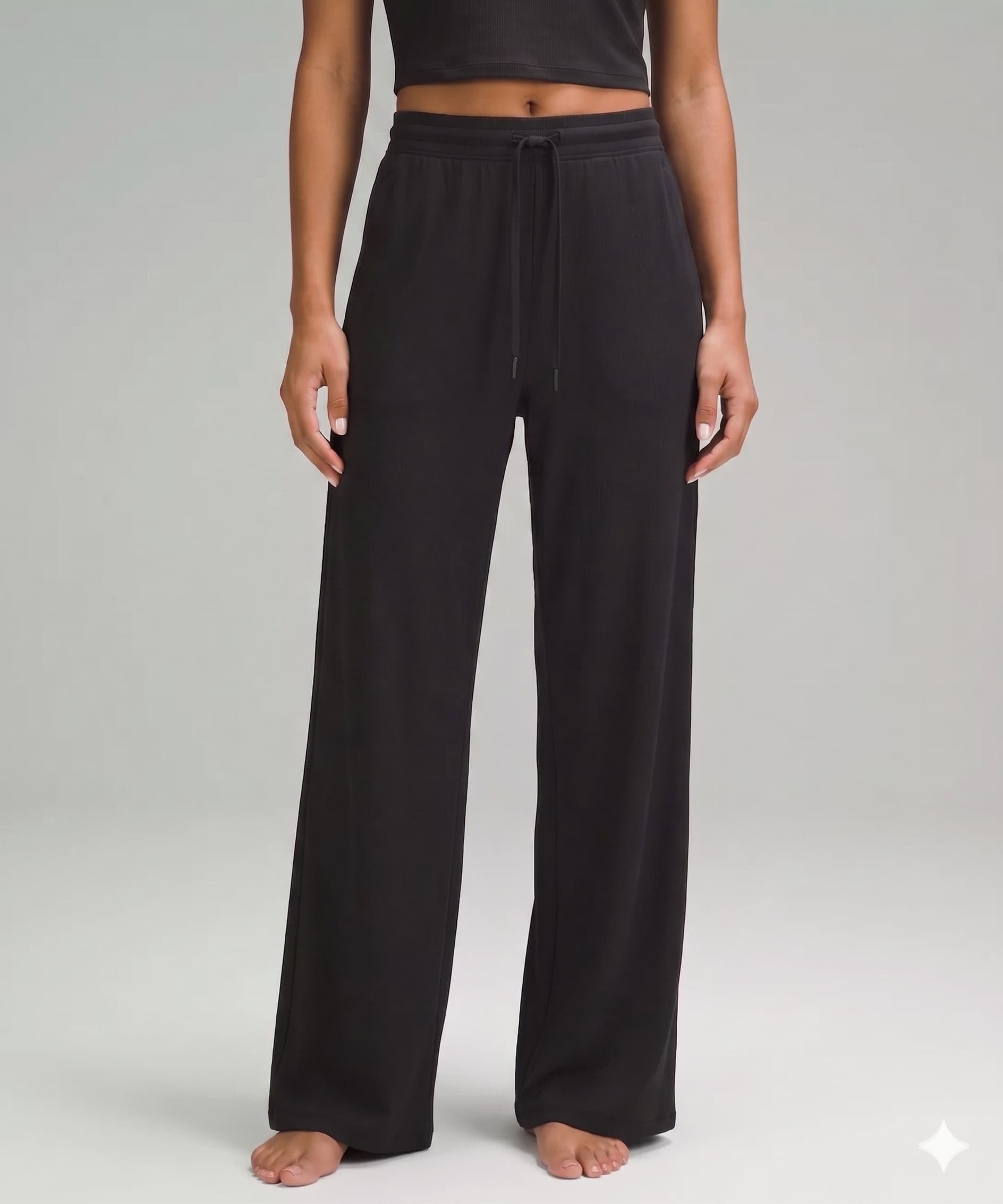 Person wearing black drawstring pants on a plain background