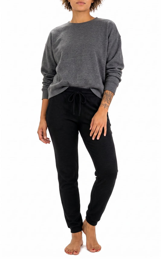 A woman modeling a dark gray long-sleeve crewneck sweatshirt and black jogger pants against a plain white background.