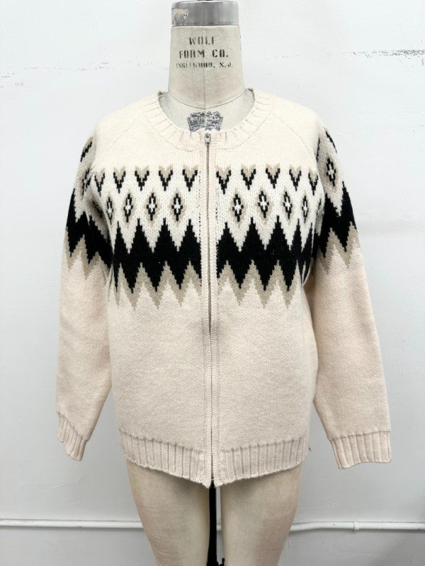 A cream-colored knit zip-up cardigan sweater with a black and cream geometric pattern across the chest and shoulders, displayed on a dress form mannequin against a white wall.